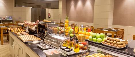 A buffet with various food items, including sandwiches, fruits, and beverages.