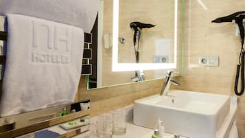 A modern bathroom with a large mirror, a sink, and a towel rack with towels.