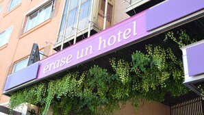 A hotel sign with the name 'érase un hotel' and green foliage growing on the wall below it. - Erase un Hotel (Madrid)