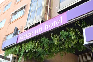 A hotel sign with the name 'érase un hotel' and green foliage growing on the wall below it.