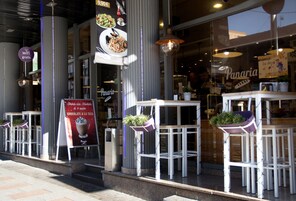 A restaurant with outdoor seating, a menu board, and a sign offering free WiFi.