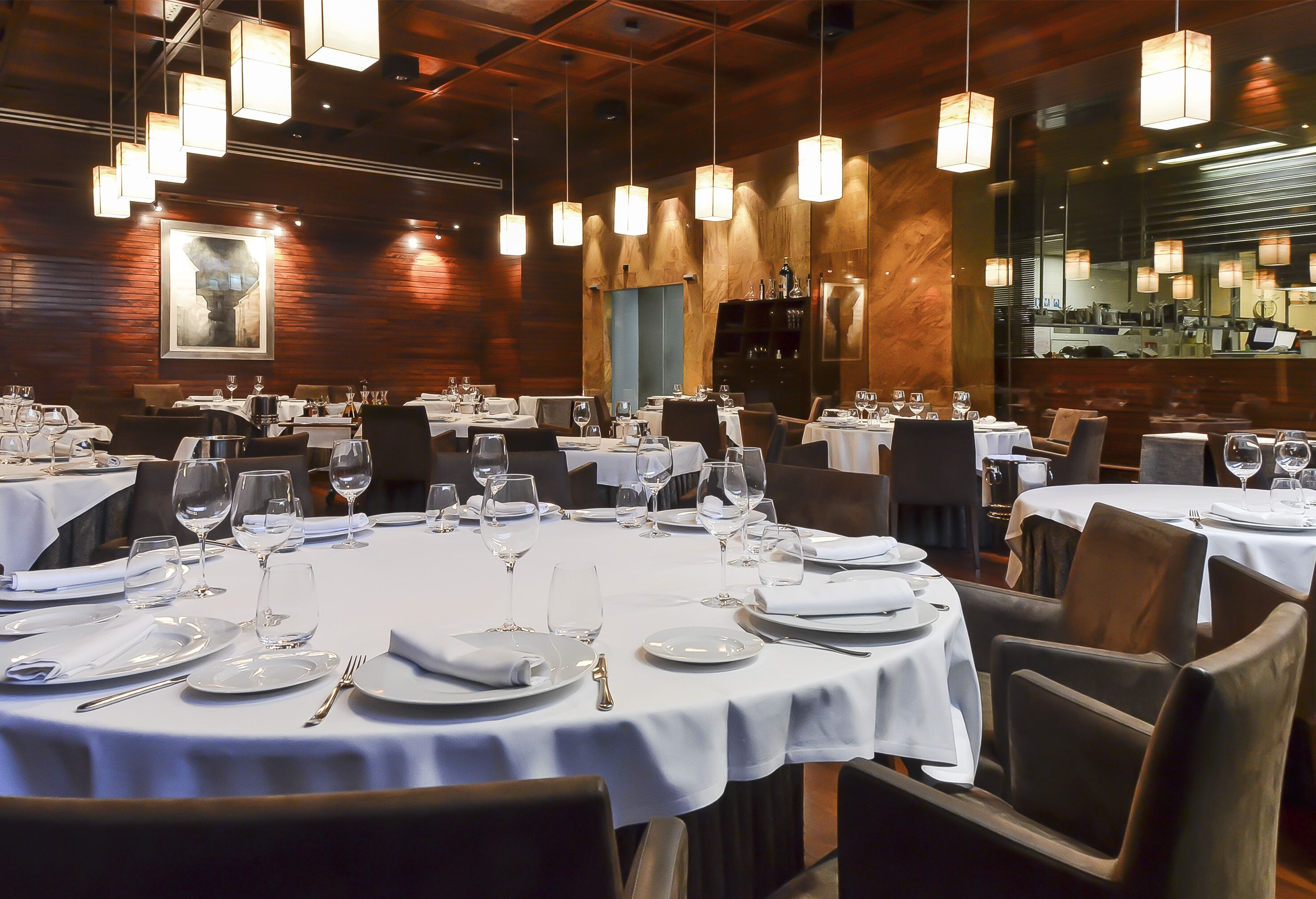 A restaurant with round tables set for dining, featuring white tablecloths and silverware.