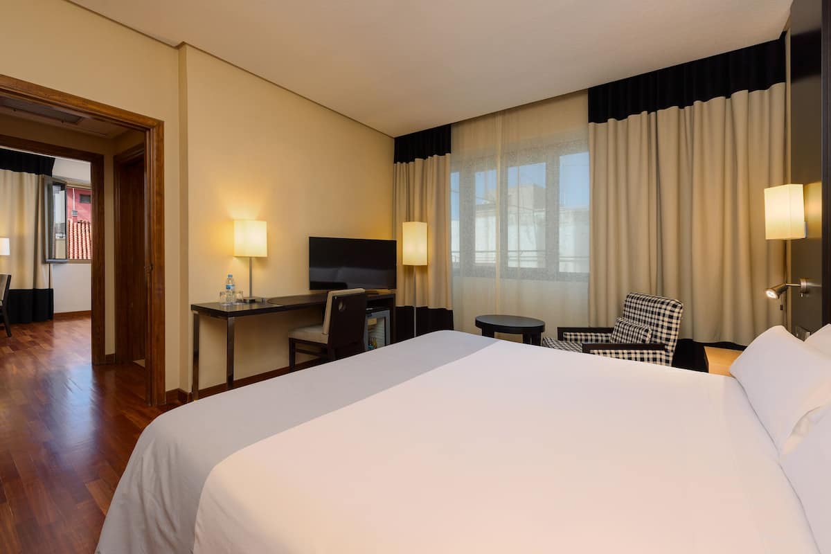Une chambre d’hôtel avec un grand lit, un bureau avec une chaise, une télévision et une petite table.
