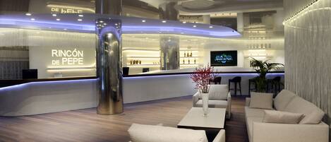 A modern hotel lobby with a reception desk, seating area, and a large pillar.