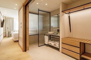 A modern bathroom with a wooden vanity, a large mirror, and a sliding door leading to a shower area.