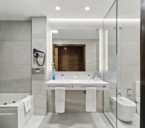 Ein modernes Badezimmer mit großem Spiegel, einer Badewanne, einer Dusche und einem Bidet.