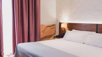 Une chambre d’hôtel avec un grand lit, un plancher en bois, une table de chevet avec une lampe et un mur décoré d’un motif.