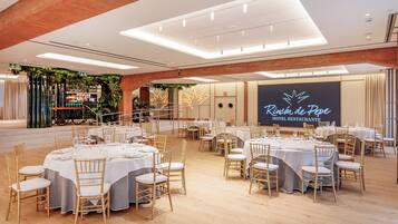 Un restaurante de hotel con mesas redondas, manteles blancos y sillas de madera.
