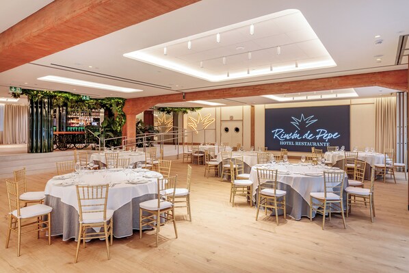 Un restaurante de hotel con mesas redondas, manteles blancos y sillas de madera.