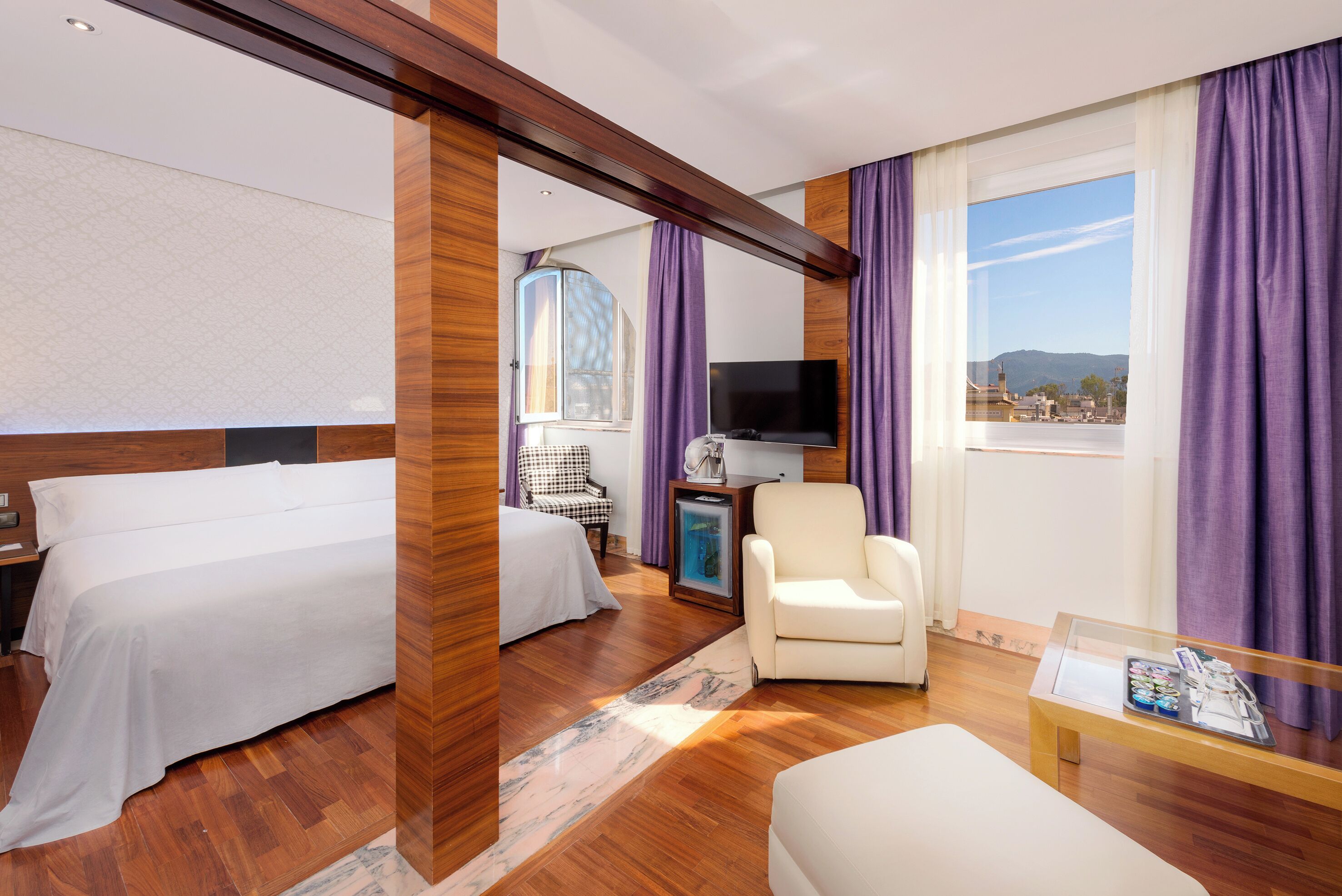 Habitación de hotel con dos camas, un televisor, una silla y ventana con vistas.