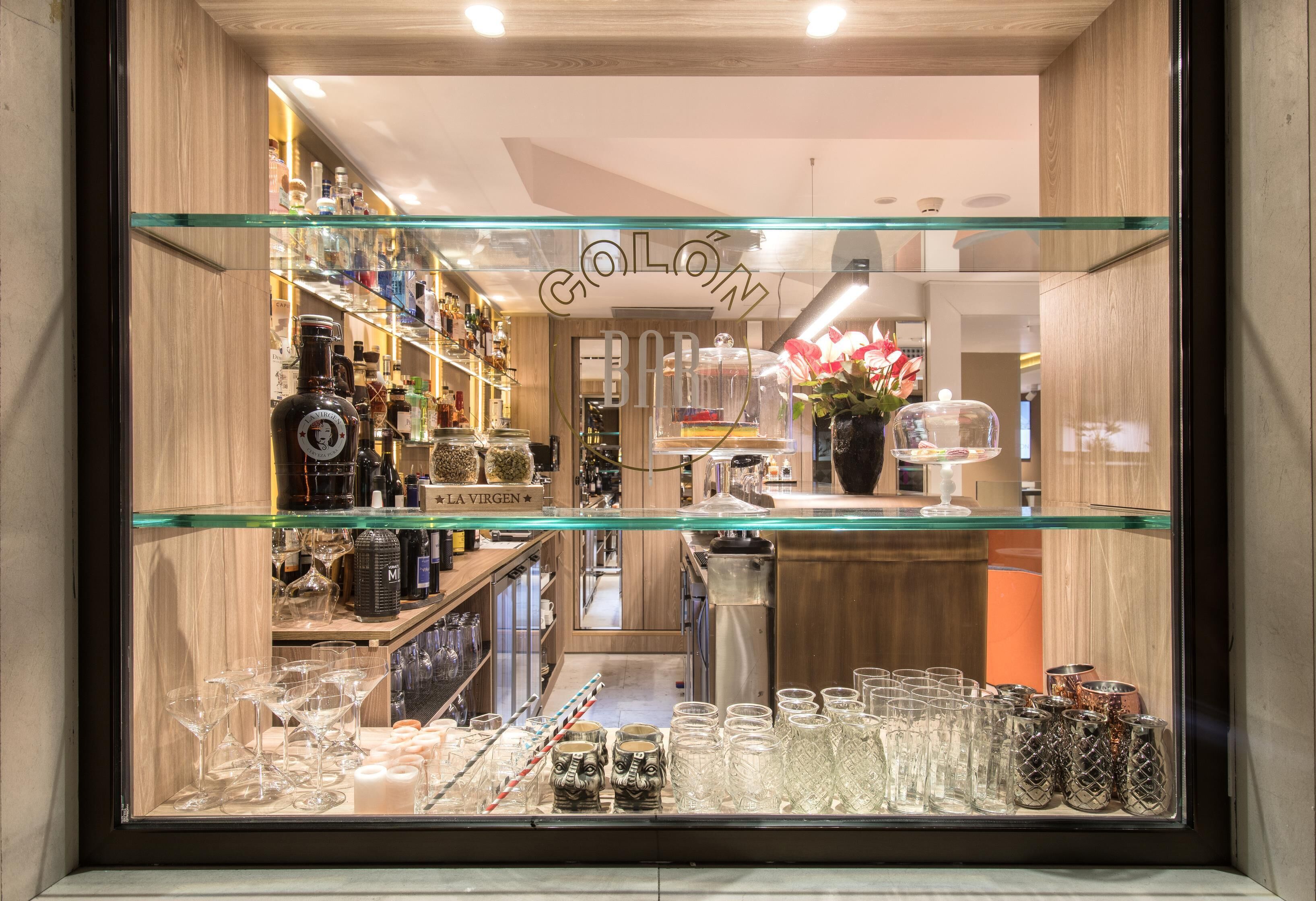 A bar with a glass display case filled with various bottles and glasses.