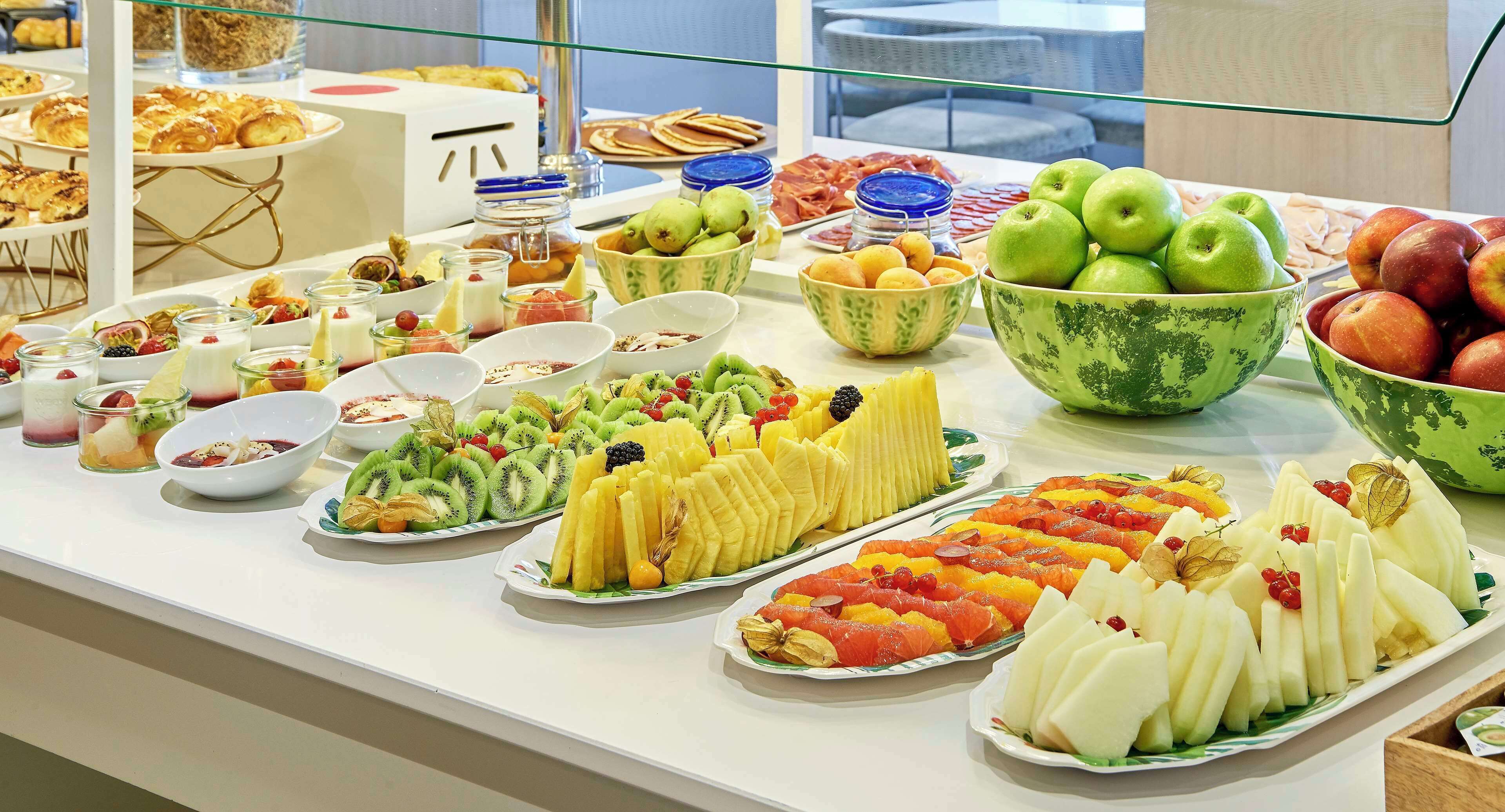 A buffet with various fruits, pastries, and desserts.