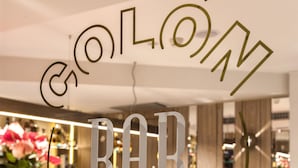 Zona de bar con diseño moderno, que incluye una silla rosa y una encimera de mármol.