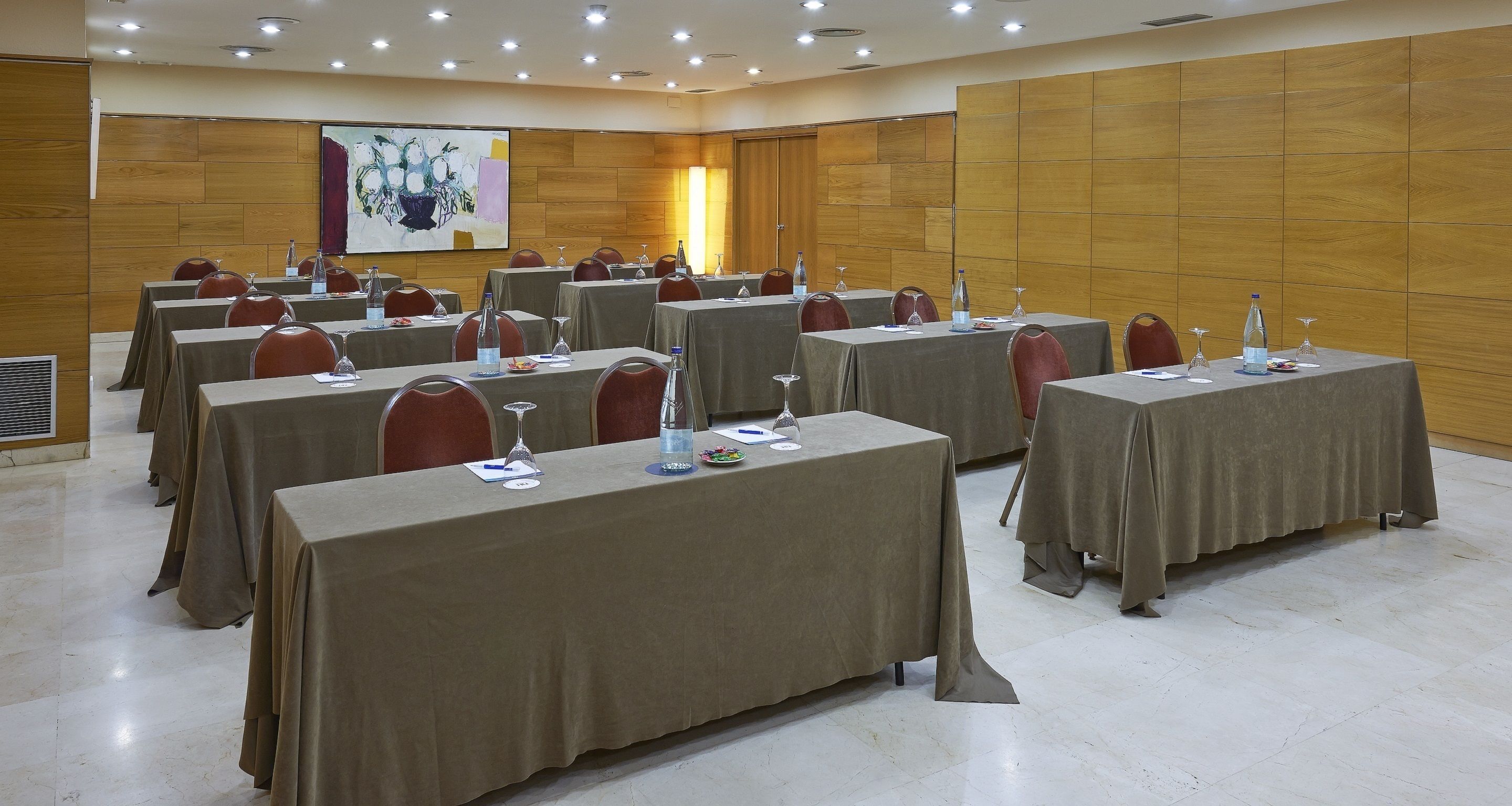 A conference room with multiple tables, each equipped with water bottles, glasses, and nameplates.