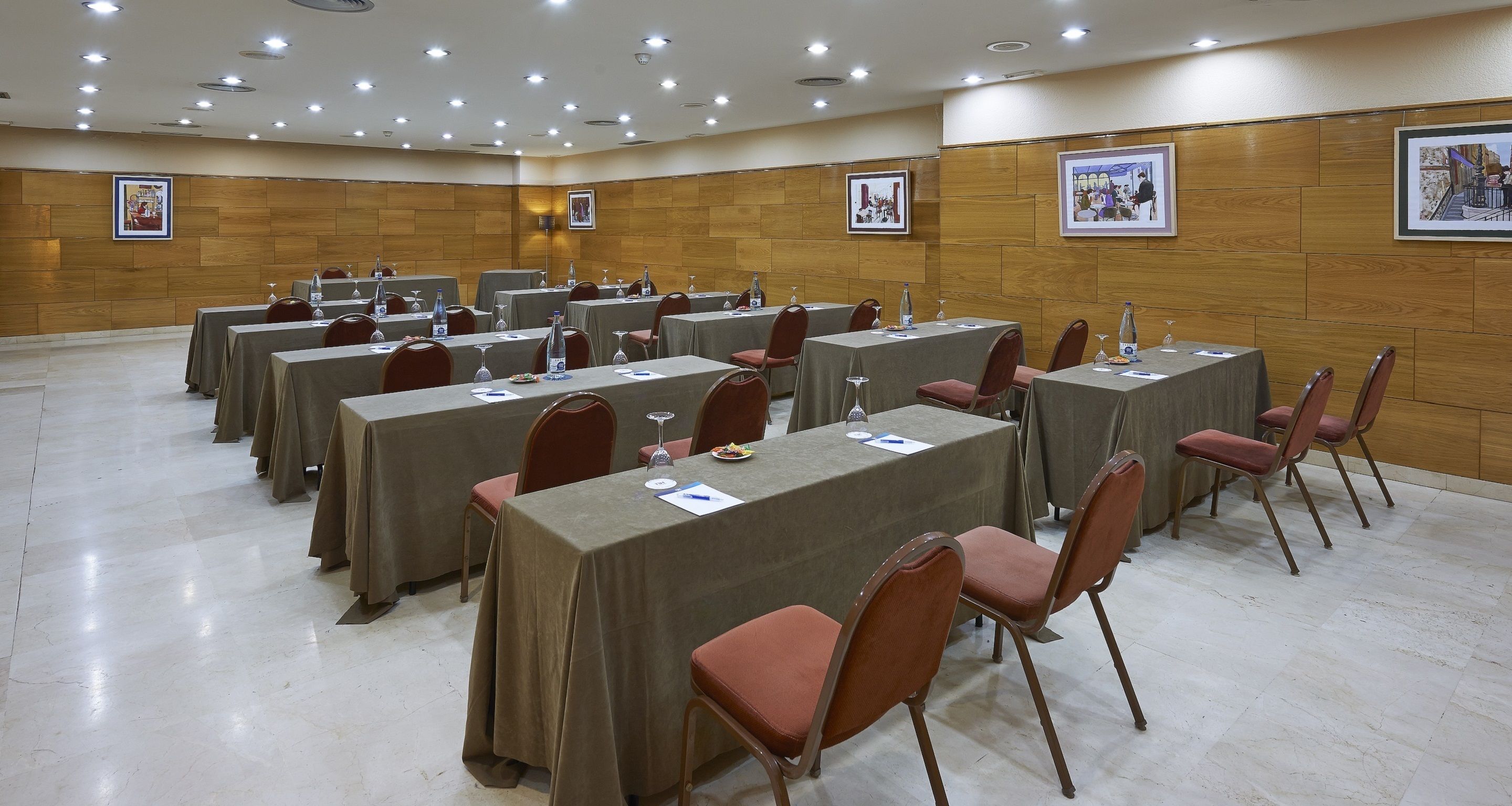 A conference room with multiple tables and chairs, equipped with water bottles and documents.