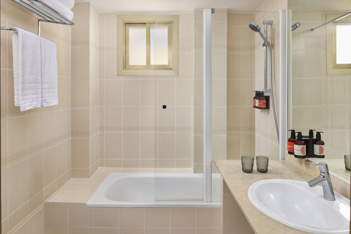 Une salle de bain avec une baignoire, une douche, un lavabo et une fenêtre.