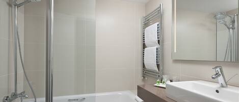 A modern bathroom with a glass shower enclosure, a bathtub, and a sink with a mirror above.