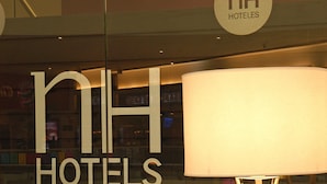Ein Hotelzeichen mit dem Schriftzug "nh hotels" und einer modernen Stehlampe.