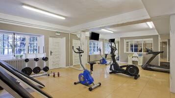 Une salle de sport équipée de matériel d’exercice, dotée d’un mur avec des miroirs et d’une porte portant l’inscription « SORTIE ».