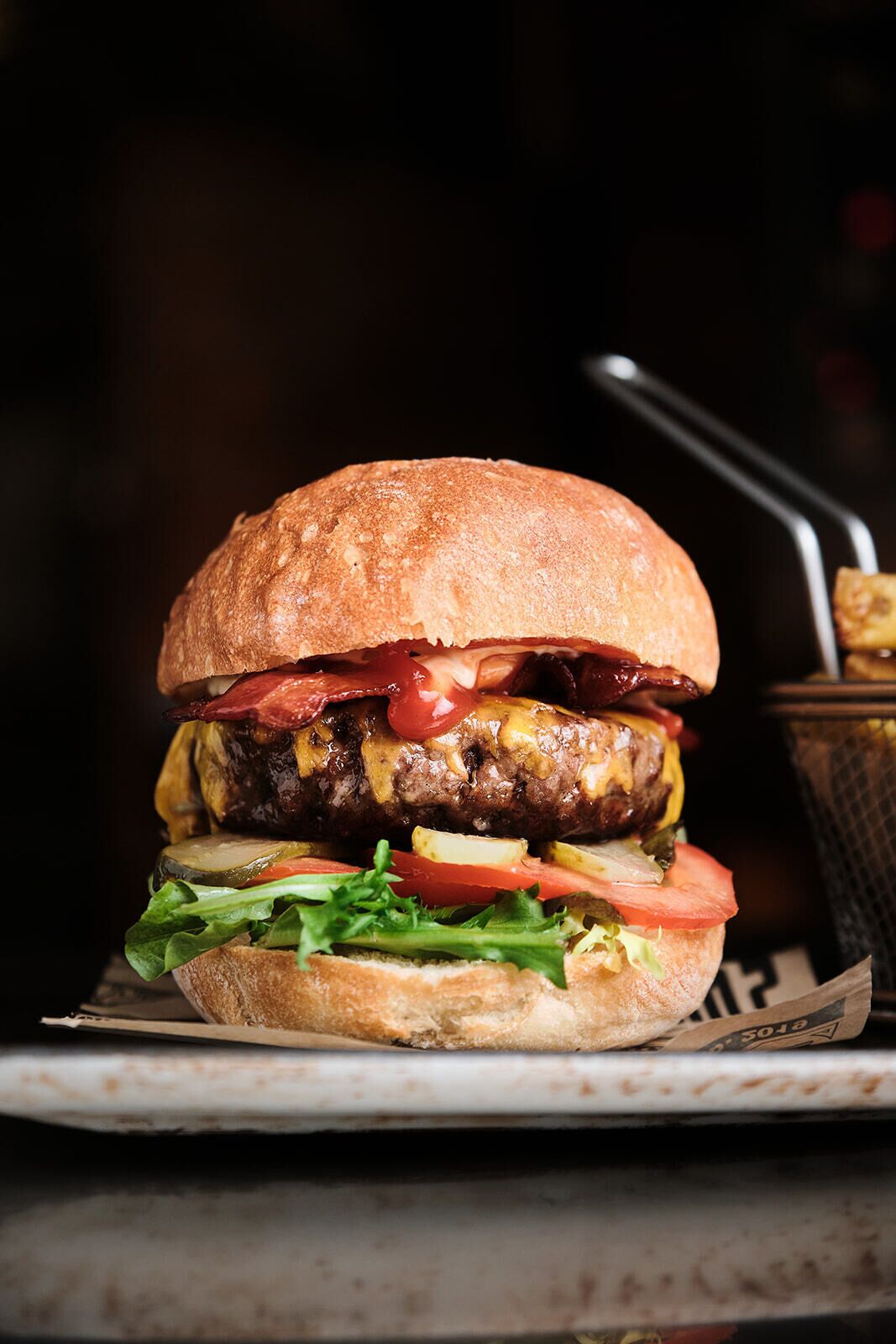 A burger with lettuce, tomato, and a bun on a plate.