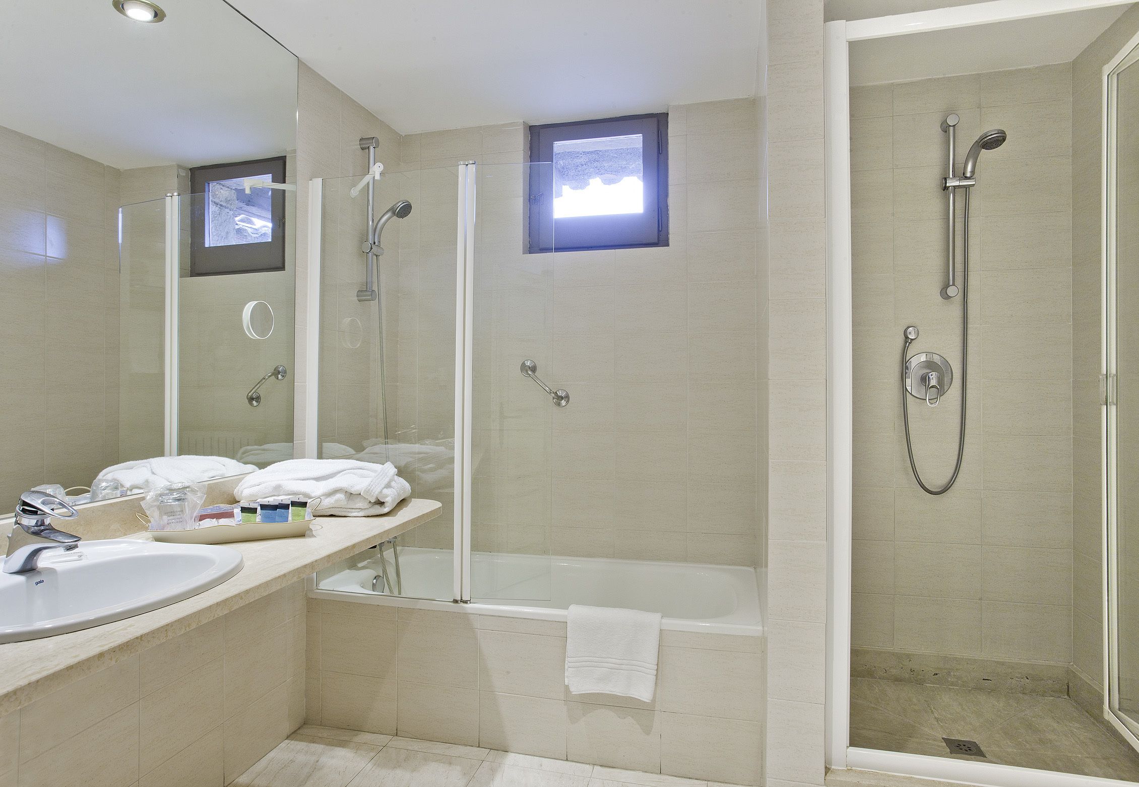 A modern bathroom with a glass-enclosed shower, a standalone bathtub, and a vanity with a sink and mirror.