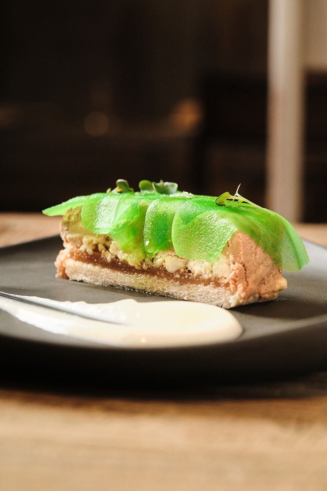 Dessert auf dunklem Teller mit weißer Soße.