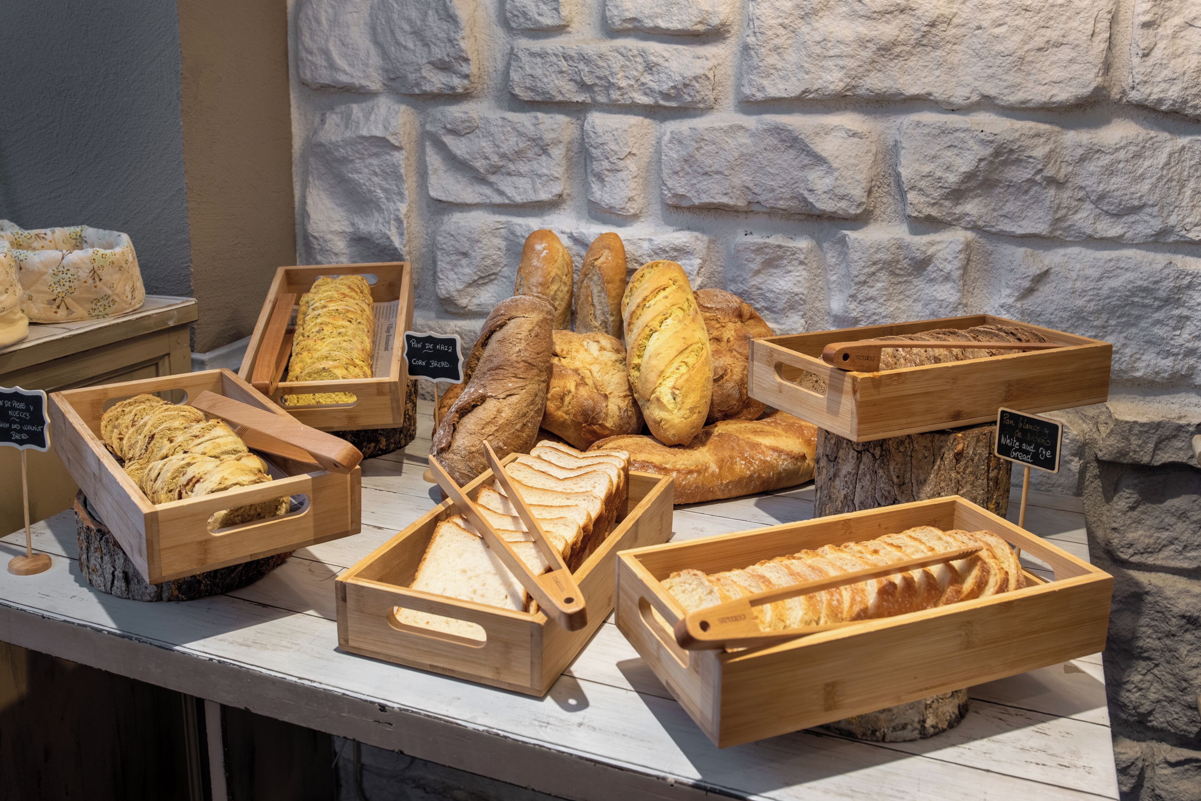 Una vitrina de panadería con diferentes tipos de pan en cajas de madera.