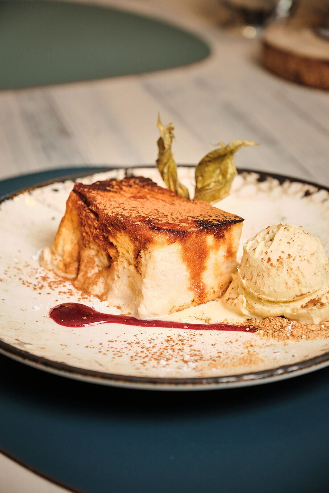 Un plato de postre con un dulce caramelizado, una bola de helado y un poco de canela espolvoreada.