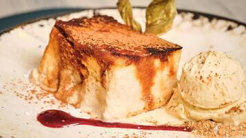 Un plato de postre con un dulce caramelizado, una bola de helado y un poco de canela espolvoreada.