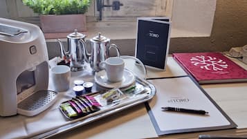 A neatly arranged breakfast table with a coffee maker, cups, a tray with snacks, and a book titled "el TORO".