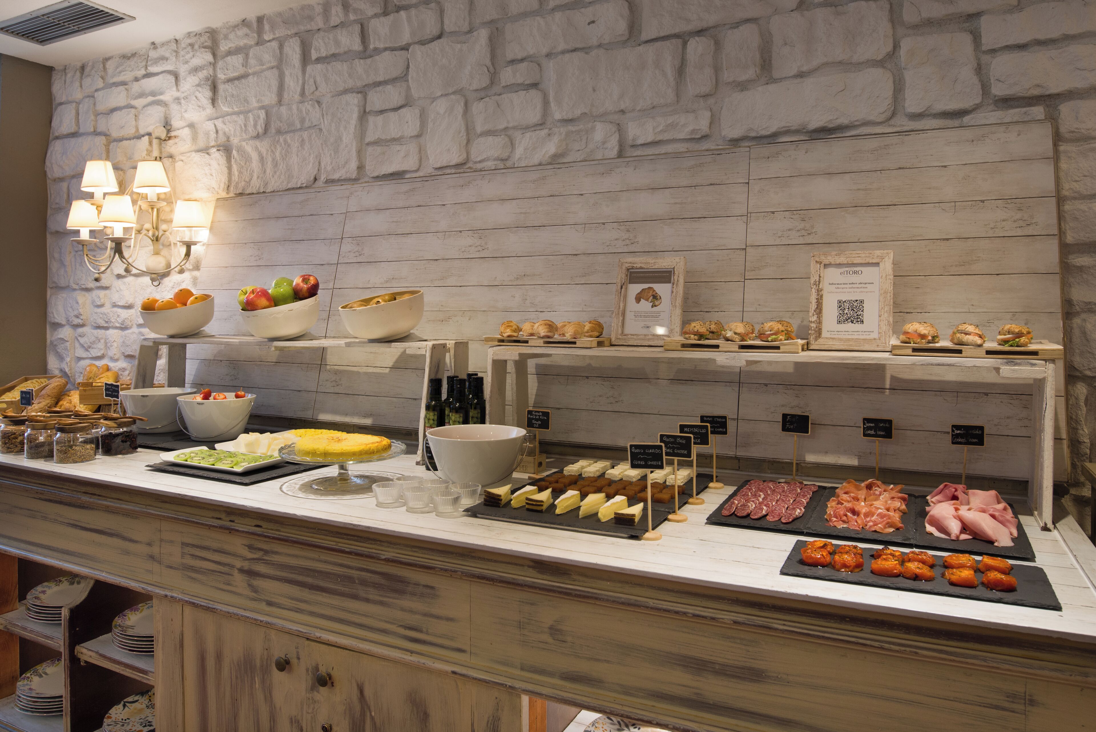 A buffet with various food items and a stone wall background.