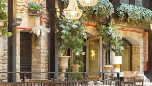 An outdoor dining area with tables and chairs, a hanging light fixture, and potted plants. - Hotel Luze El Toro (Berrioplano)