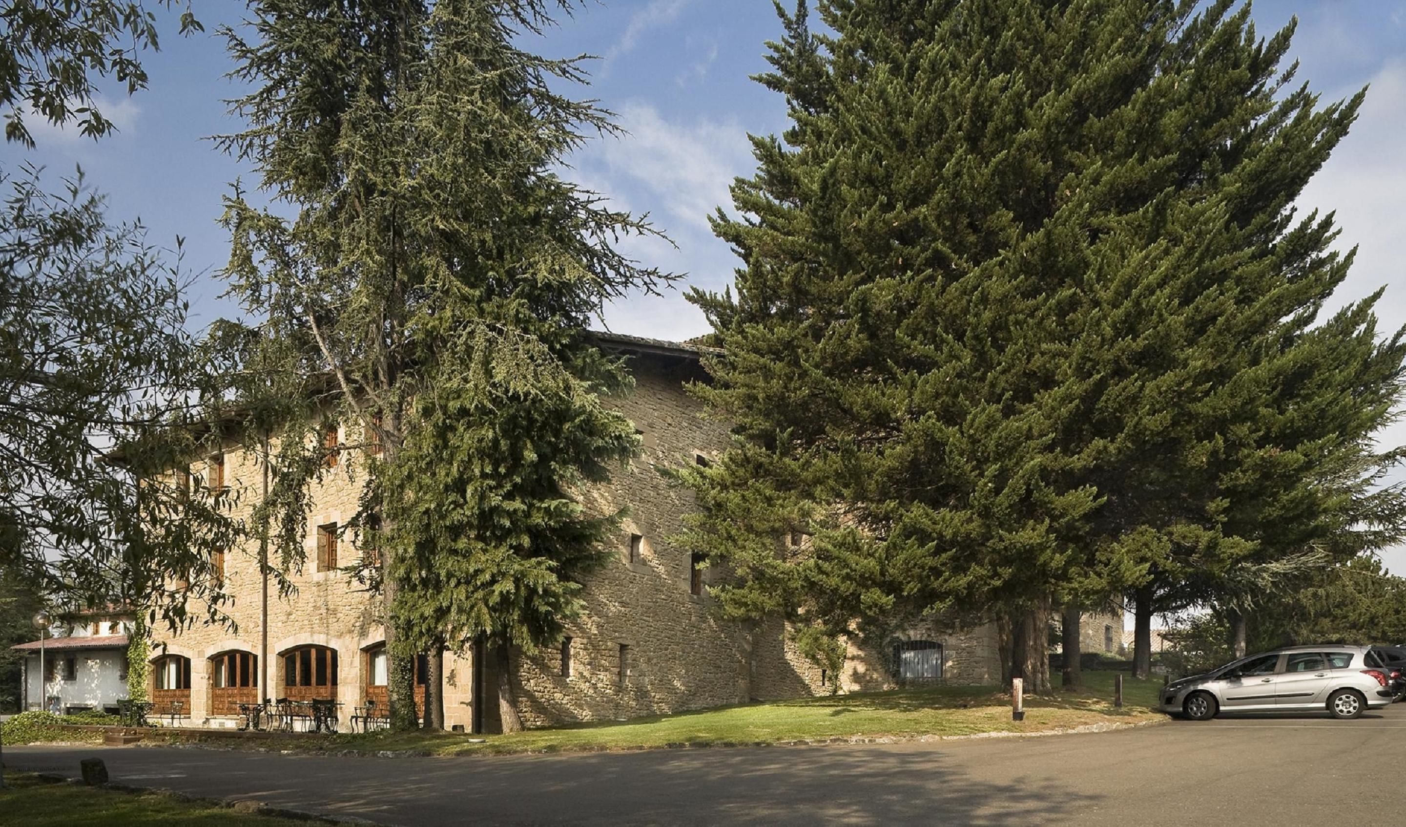 Un edificio de piedra con ventanas arqueadas y un gran árbol en primer plano.