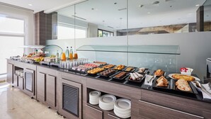 Un buffet de petit-déjeuner moderne proposant une variété d’aliments et de boissons, des cloisons en verre et un design épuré et contemporain.