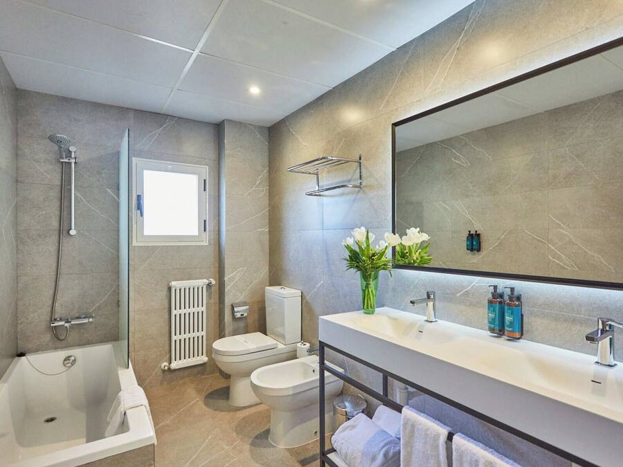 A modern bathroom with a bathtub, toilet, and shower.