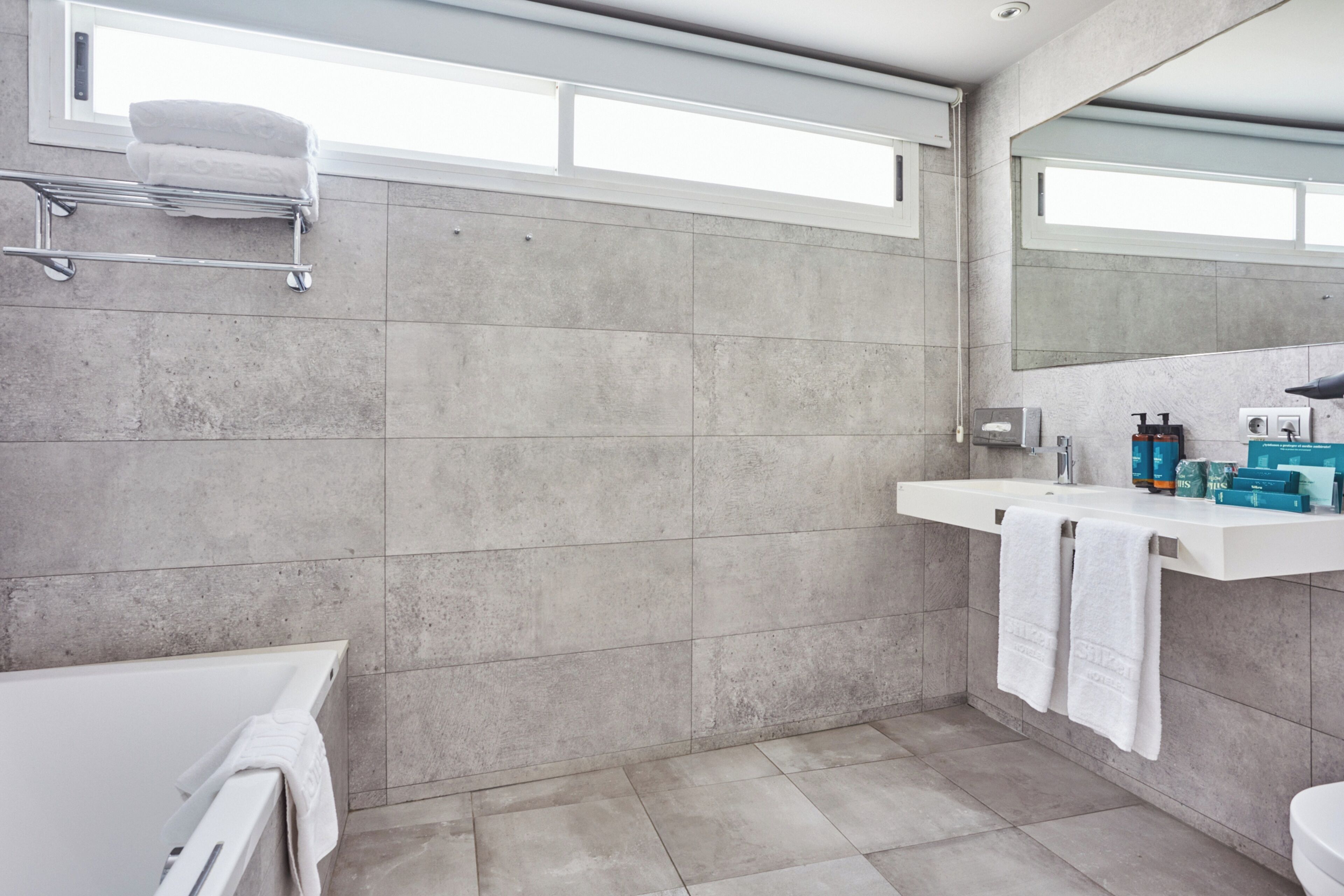 Ein modernes Badezimmer mit einer Badewanne, einem weißen Waschbecken mit Spiegel und einem Handtuchhalter.