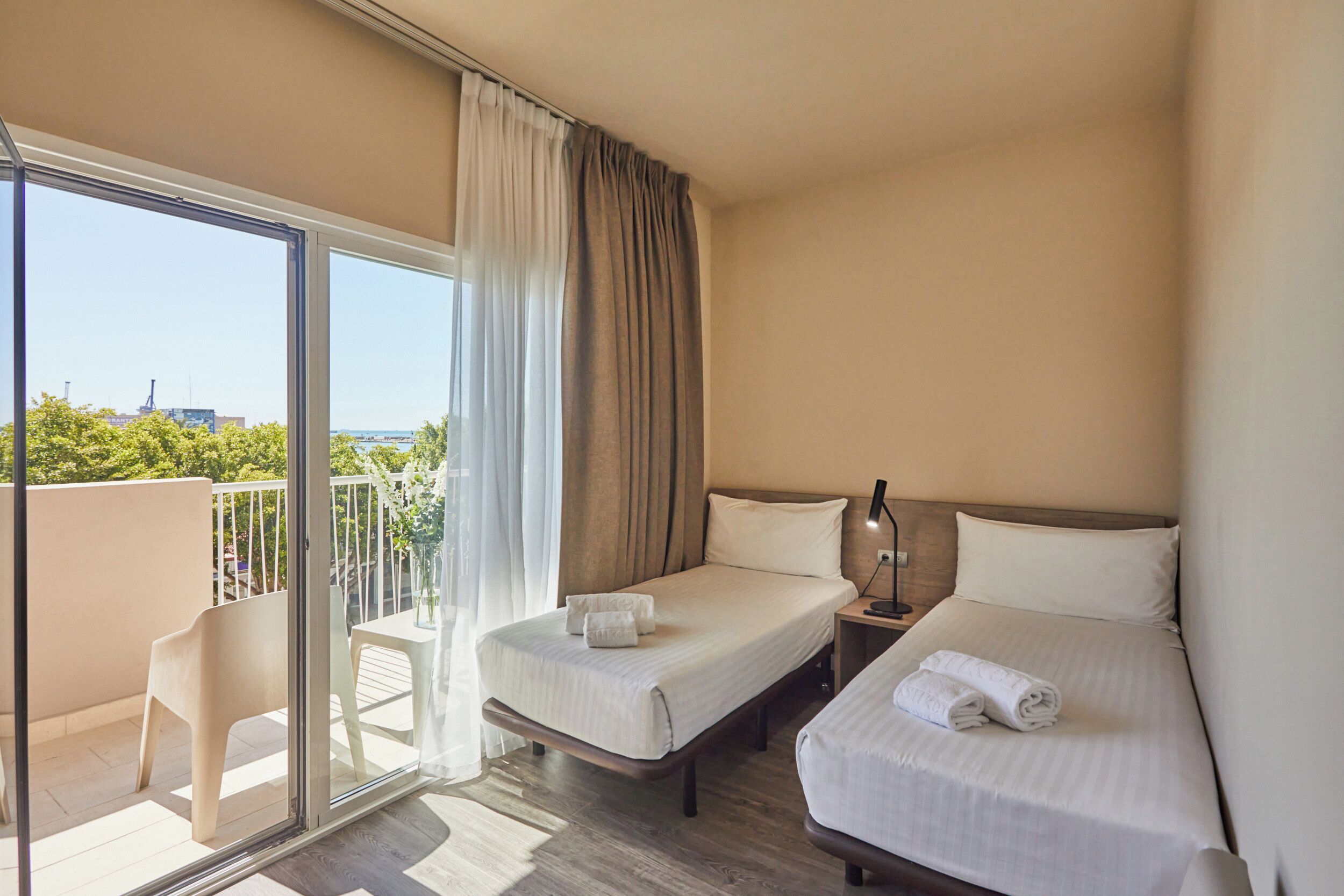 A hotel room with two beds, a balcony, and a view of the city.