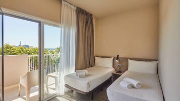 A hotel room with two beds, a balcony, and a view of the city.