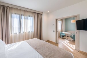 A hotel room with a bed, a desk, and a TV.