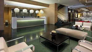 A modern hotel lobby with a reception desk, seating area, and staircase. - NH Collection Villa de Bilbao (Bilbao)