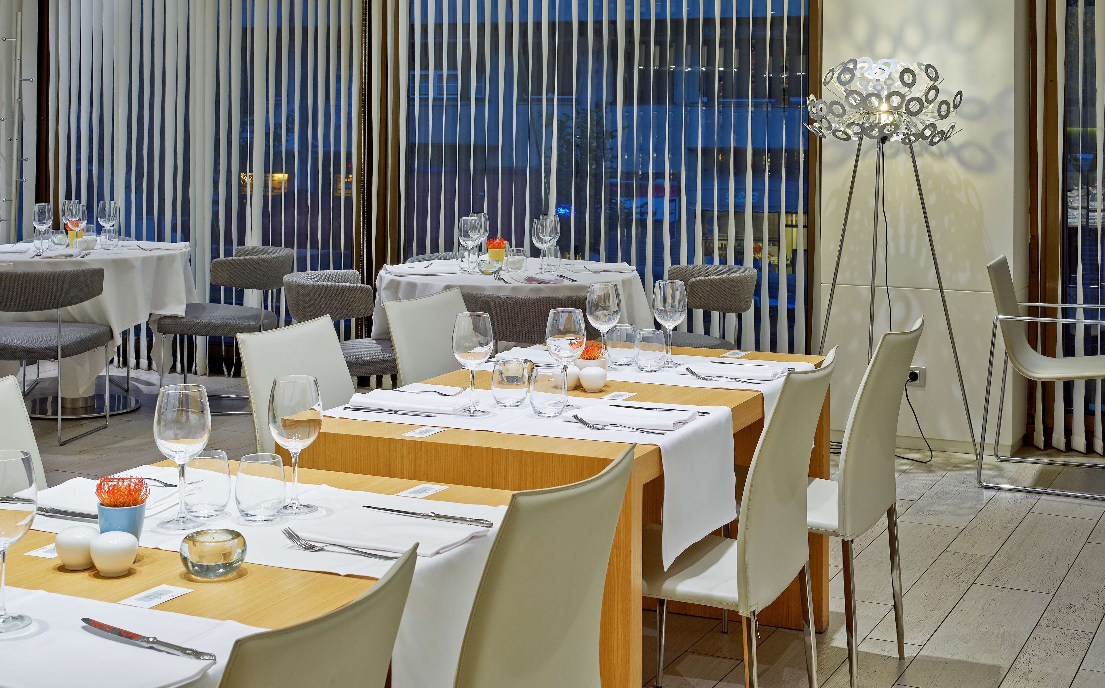 A restaurant with multiple tables set for dining, featuring white tablecloths, neatly arranged cutlery, and wine glasses.
