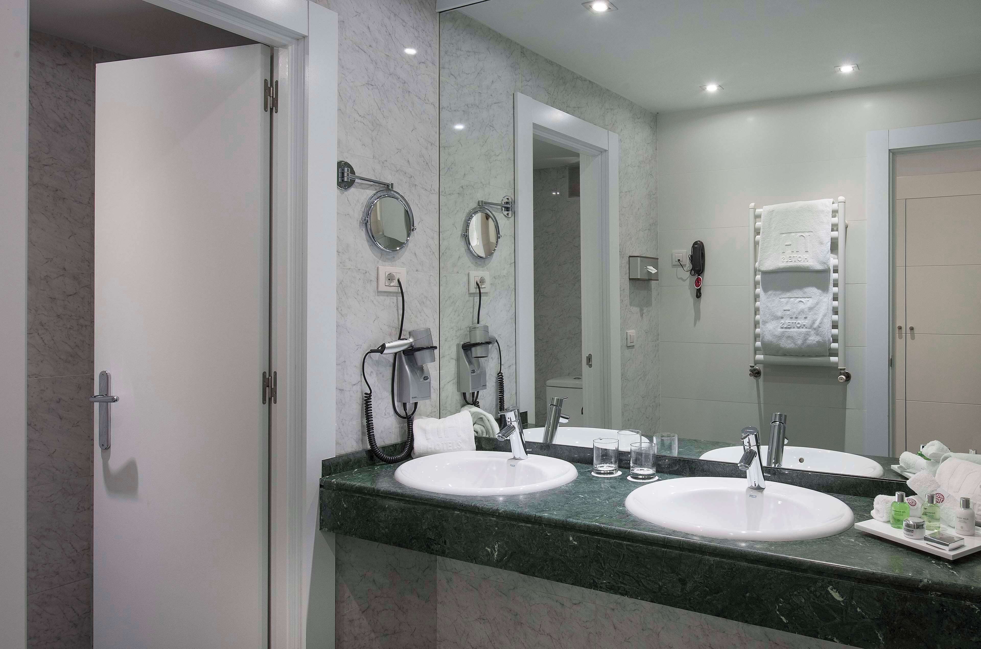 Un baño con dos lavamanos, un espejo grande y un perchero para toallas.