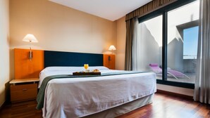 A hotel room with a bed, bedside lamps, a breakfast tray, and a large window with a view of the outside. - Hotel Villacarlos (Valencia)