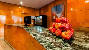 A modern hotel lobby with a marble reception desk, a fruit display, and a large painting on the wall. - Hotel Villacarlos (Valencia)