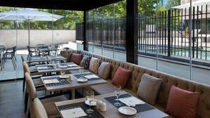 Een restaurant met terras, inclusief een lange bank en tafels, met uitzicht op het buitengebied.