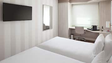 Habitación de hotel con una cama grande, un escritorio con una silla, un televisor de pantalla plana y un espejo amplio.