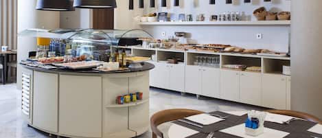 A modern breakfast bar with a variety of food items and beverages, a seating area with a table set for two, and a clean, minimalist decor.