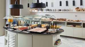 Een buffet met diverse gerechten en drankjes, een glazen vitrine en hangende pendelverlichting.
