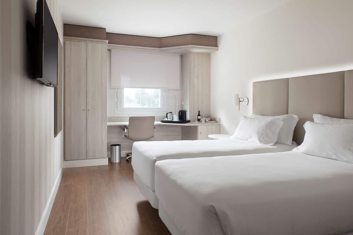 Een hotelkamer met twee bedden, een bureau en een zithoek.