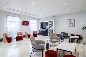 A modern hotel lobby with seating areas, a reception desk, and a minibar. - Exe Pozuelo (Pozuelo de Alarcon)